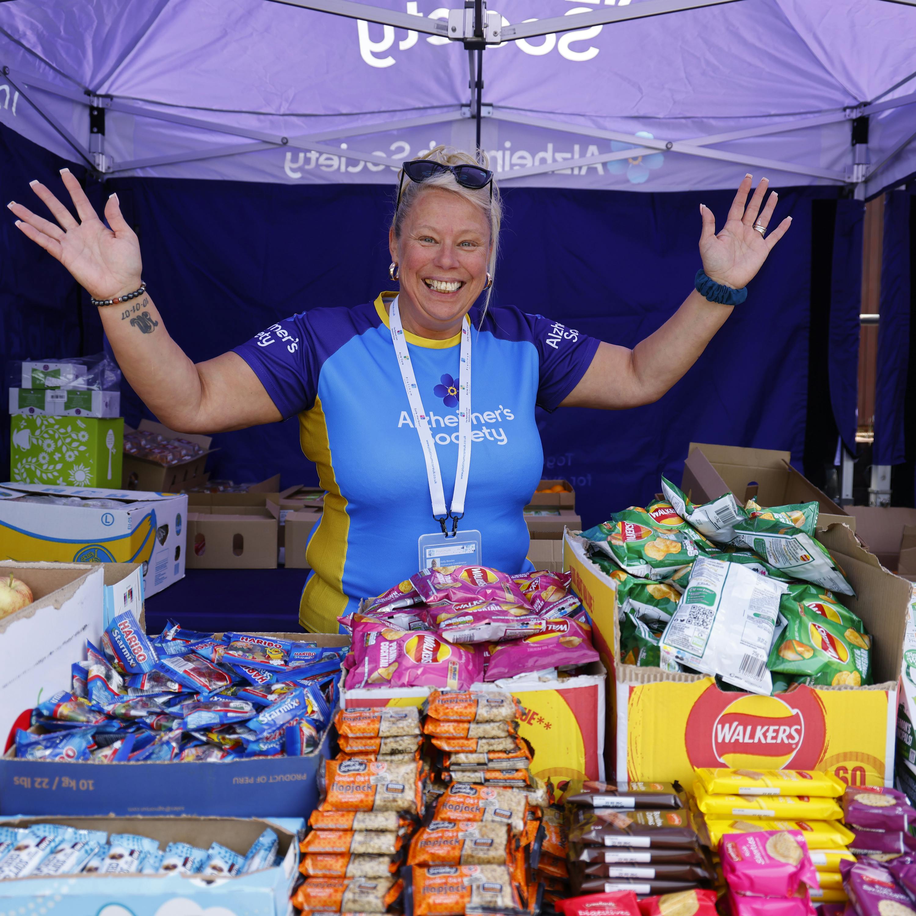 Trek26 volunteer standing behind a snack table, smiling.