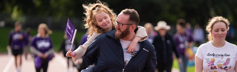 Man holding a child on his back waving a flag