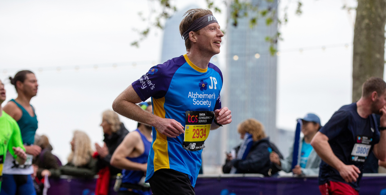 A male runner mid-race pictured sideways on wearing an Alzheimer’s Society running top.