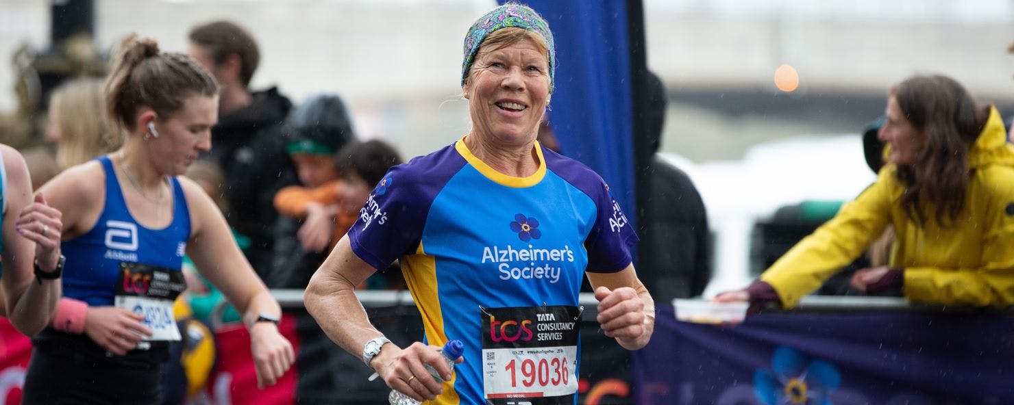 Woman smiling and running in an Alzheimer's Society top.