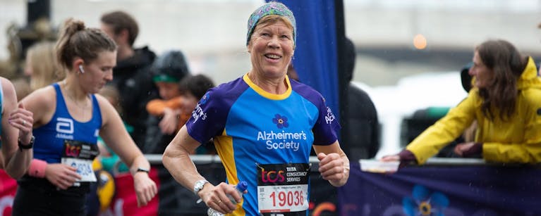 Woman smiling and running in an Alzheimer's Society top.