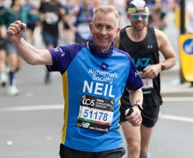 Man smiling and running in an Alzheimer's Society marathon top.