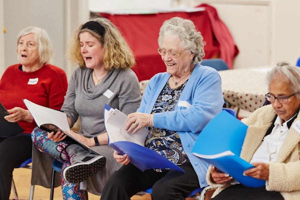 Group of people seated and smiling, with folders in their hands