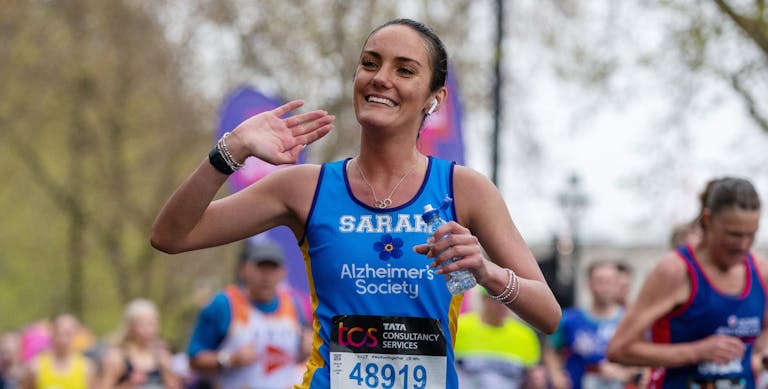Woman smiling and running in an Alzheimer's Society marathon top.