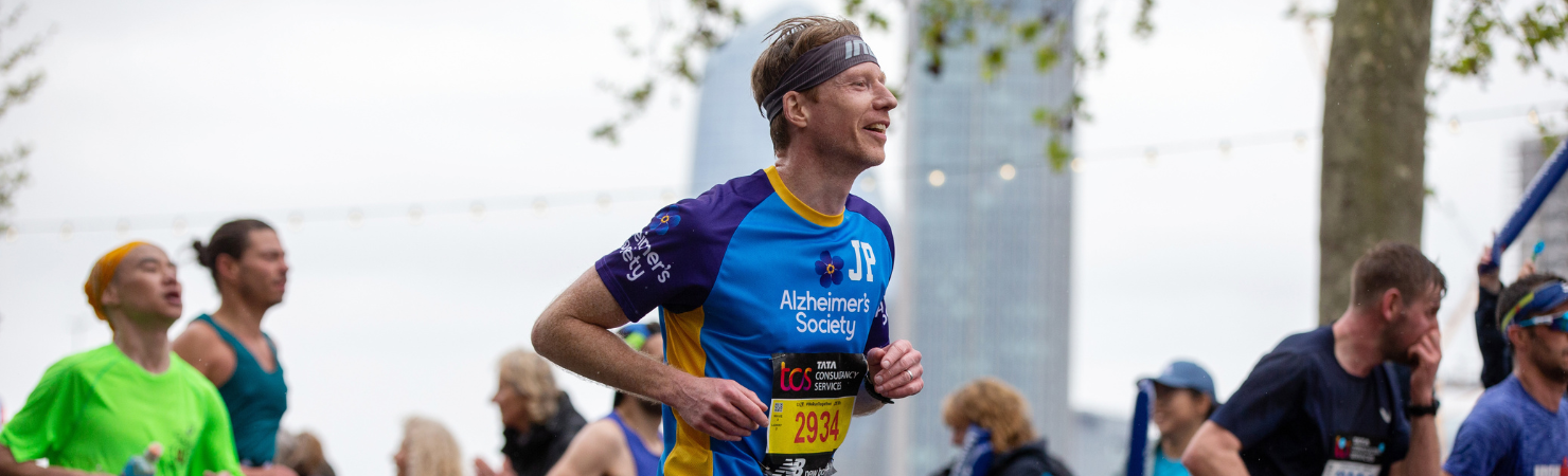 A male runner mid-race pictured sideways on wearing an Alzheimer’s Society running top.