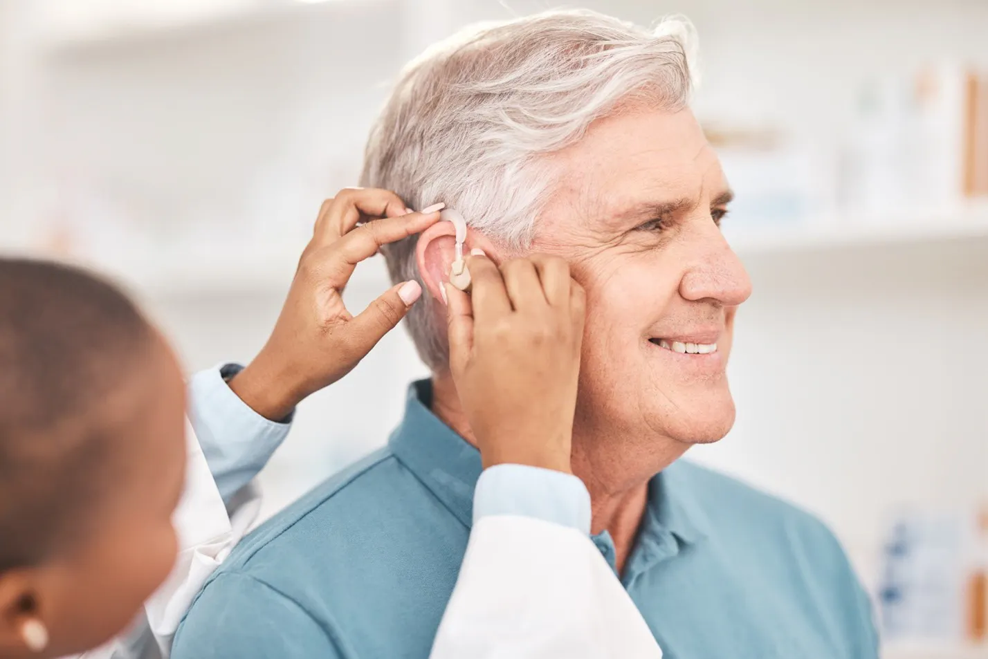 Audiologist adjusting hear aid on patient in Lely, Marco Island and East Naples FL