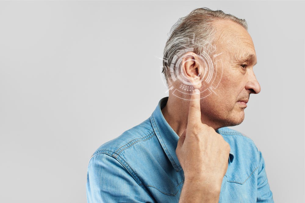 Man with hearing loss pointing to his ear in East Naples, FL