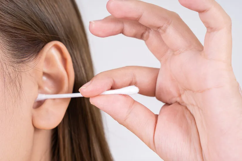 A woman cleaning her ear with a Q-tip