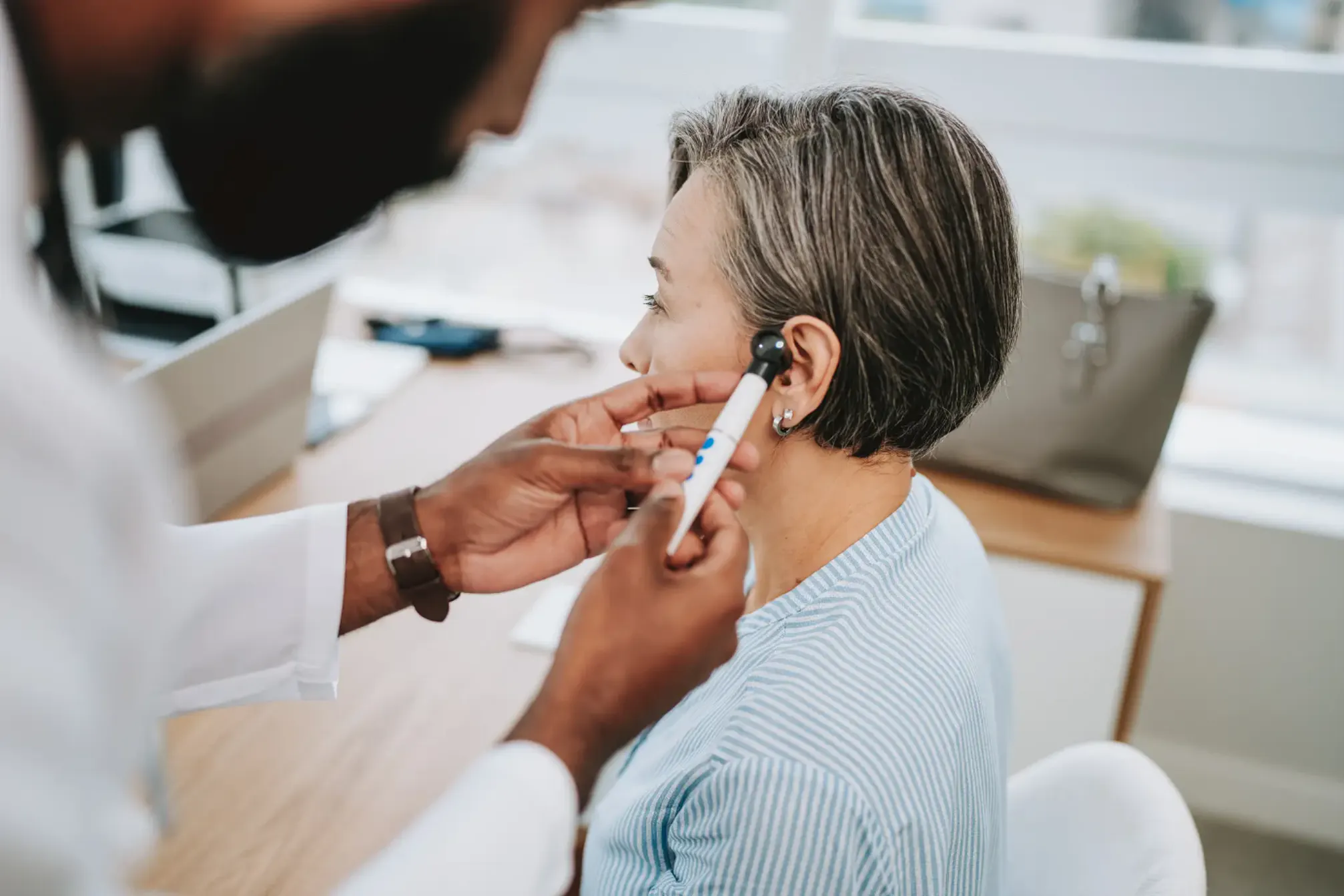A woman undergoing a professional hearing evaluation conducted by an audiologist.