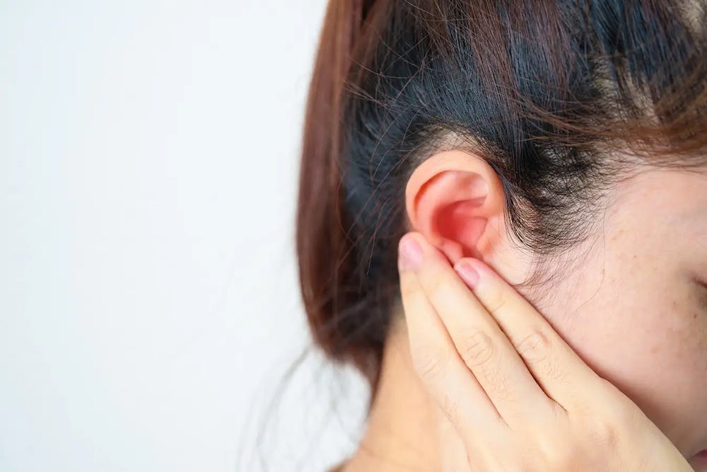 Young woman holding swollen earlobe in Lely & East Naples