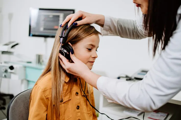 A girl using a hearing aid by American Medical Hearing Centers 
