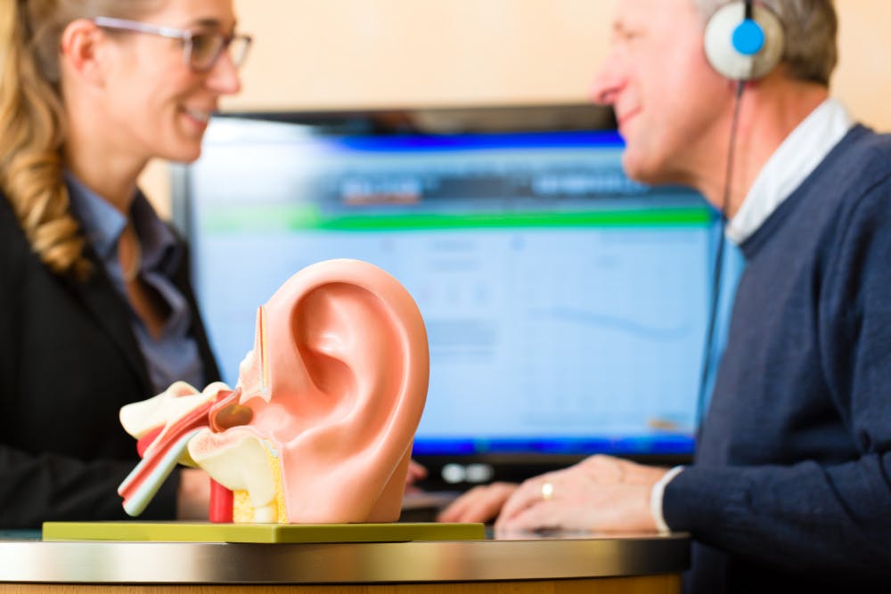 Ear 3D model with a blur background of patient being examined by an audiology doctor in Lely & East Naples