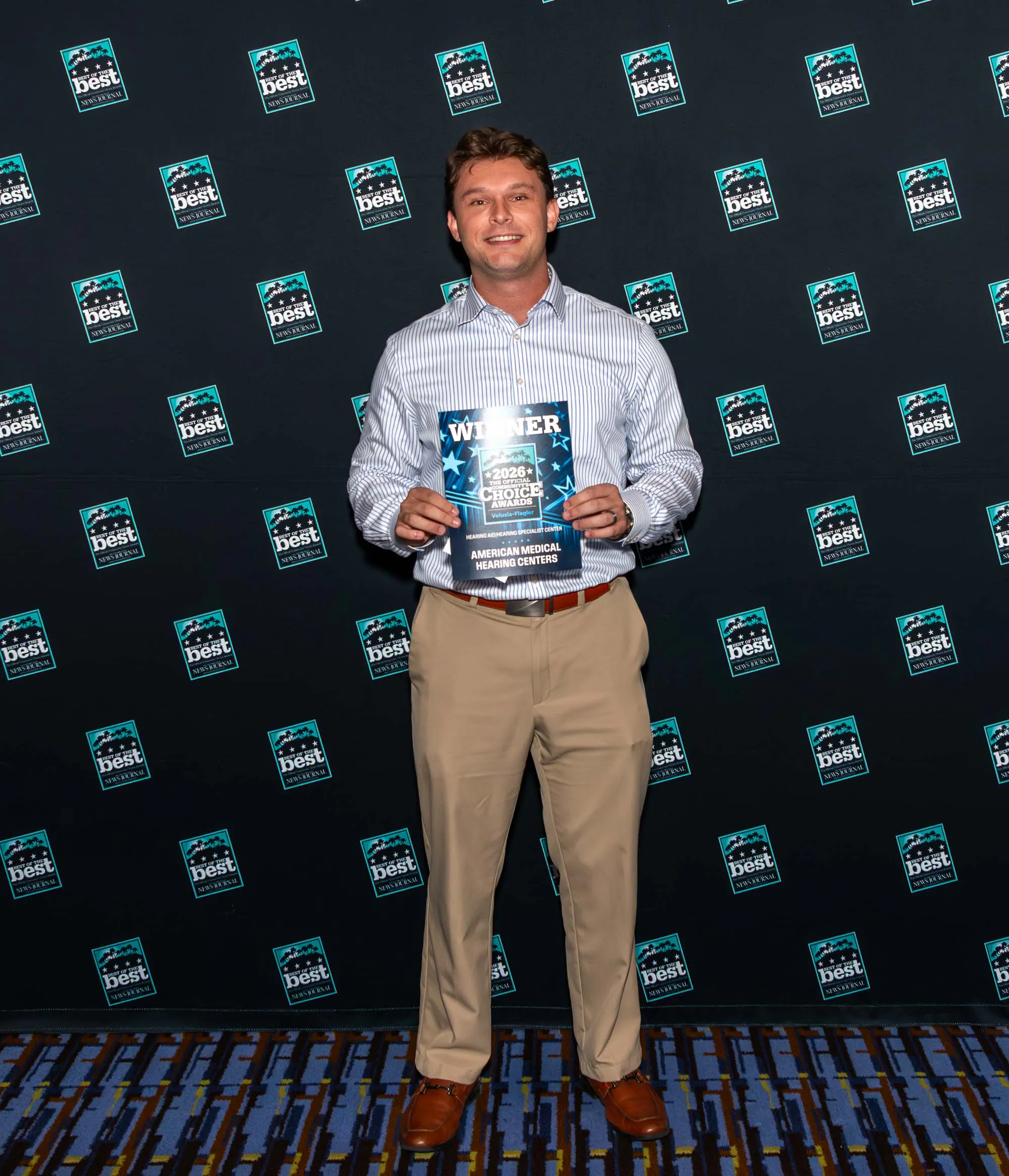 An American Medical Hearing Centers team member holding the 2026 Volusia-Flagler winner award.