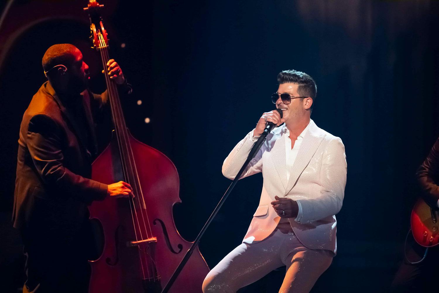 Man singing on stage with a cello player next to him