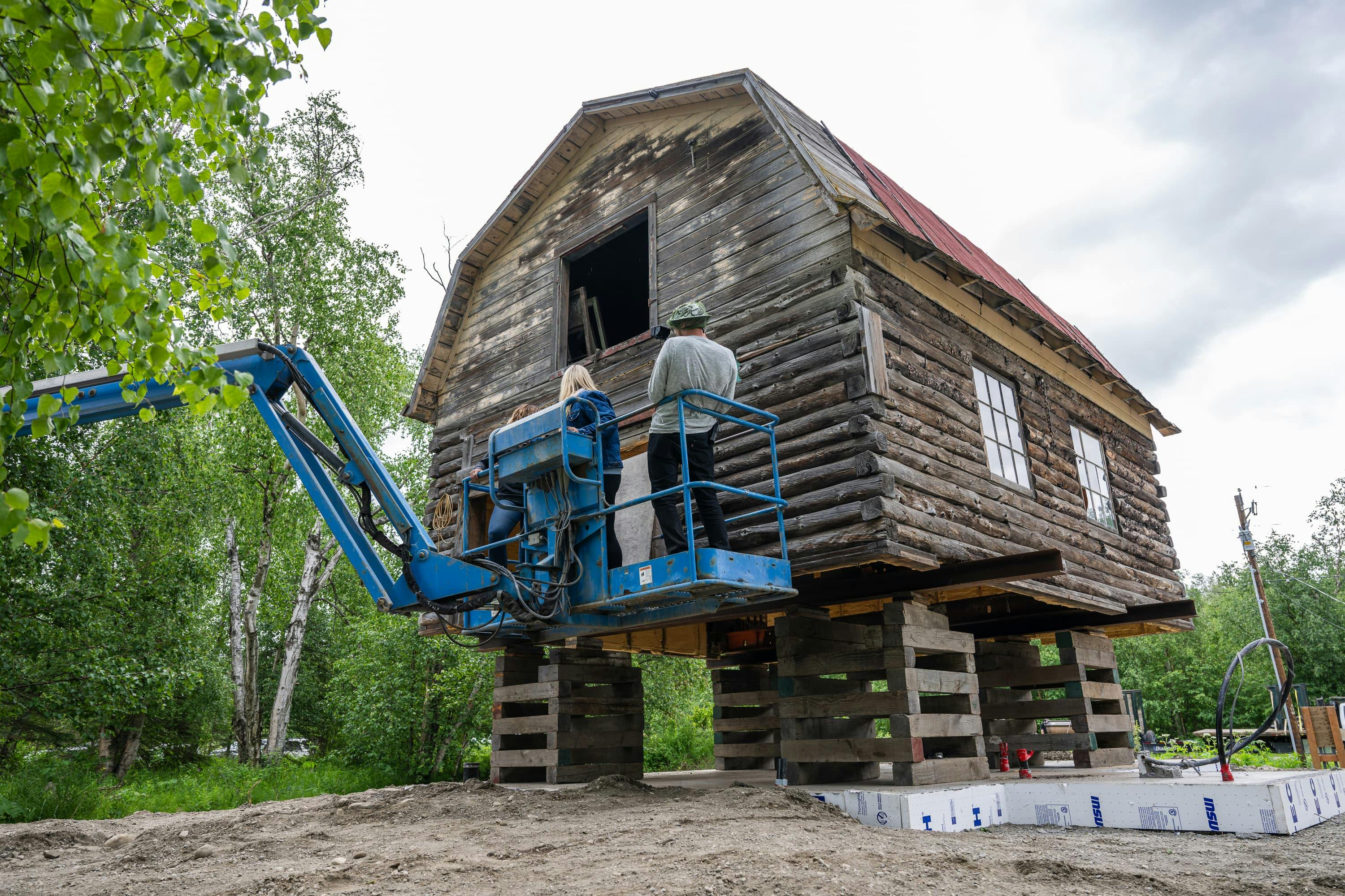 People on a crane looking at an old barn