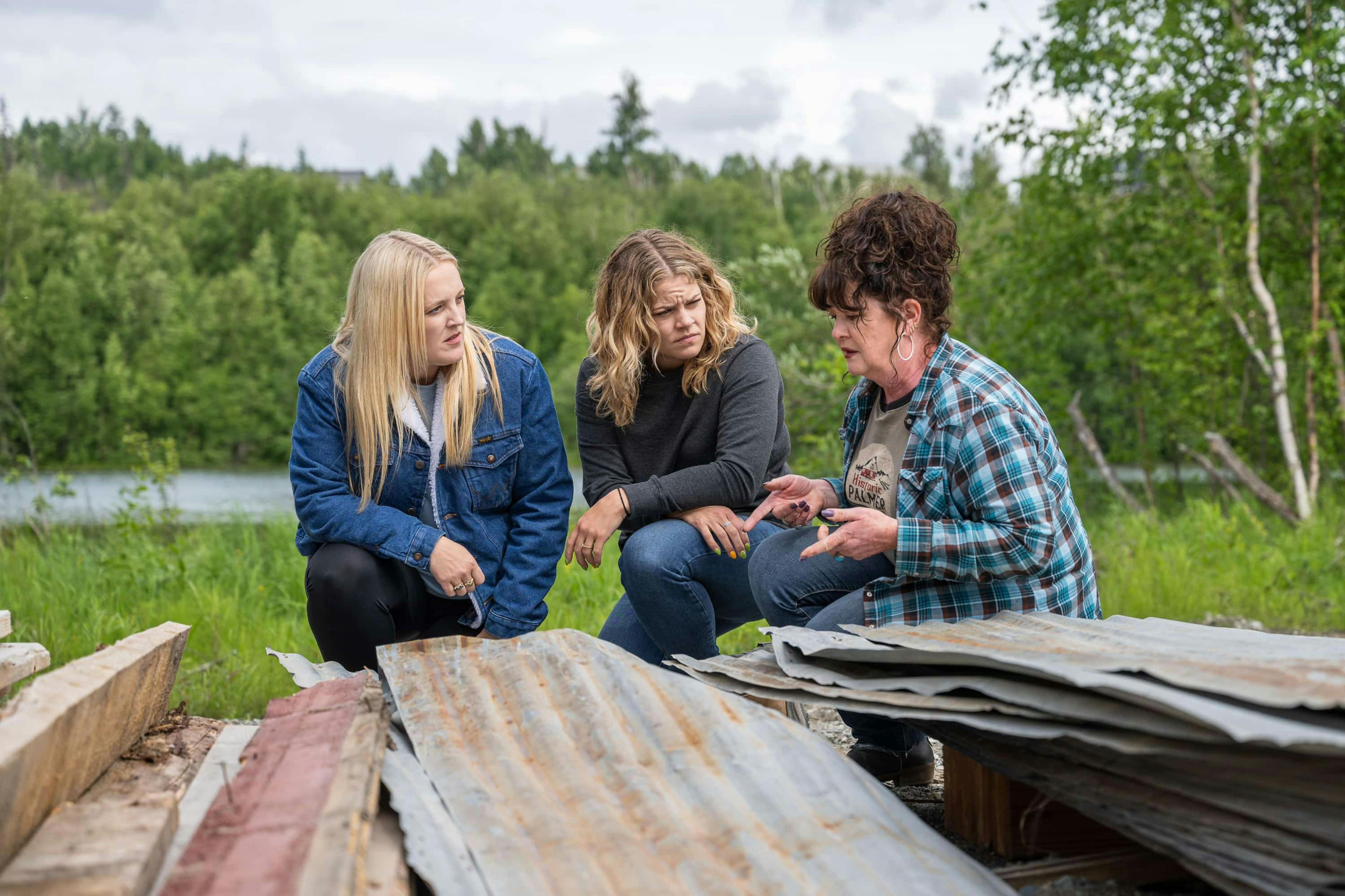 Three women sat talking in front of wood