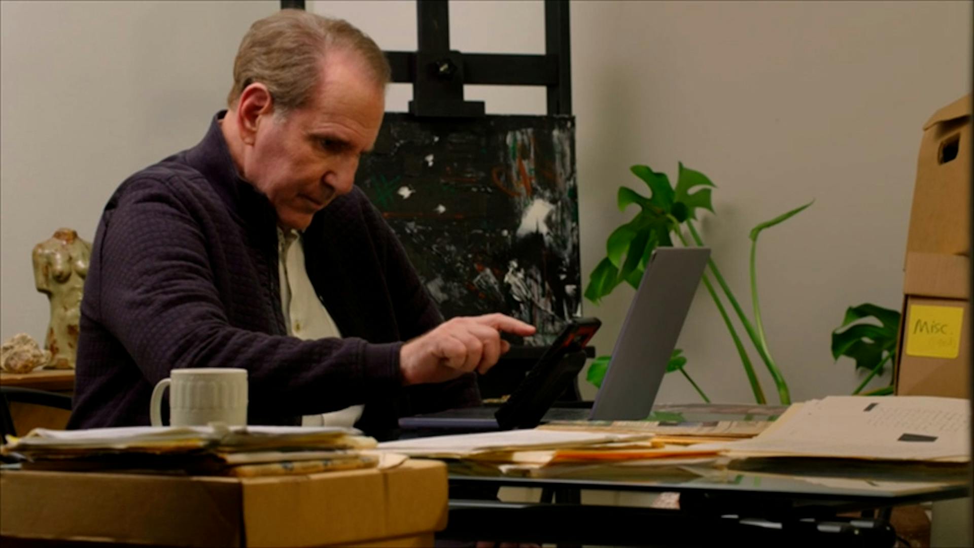 Man texting on phone in front of laptop