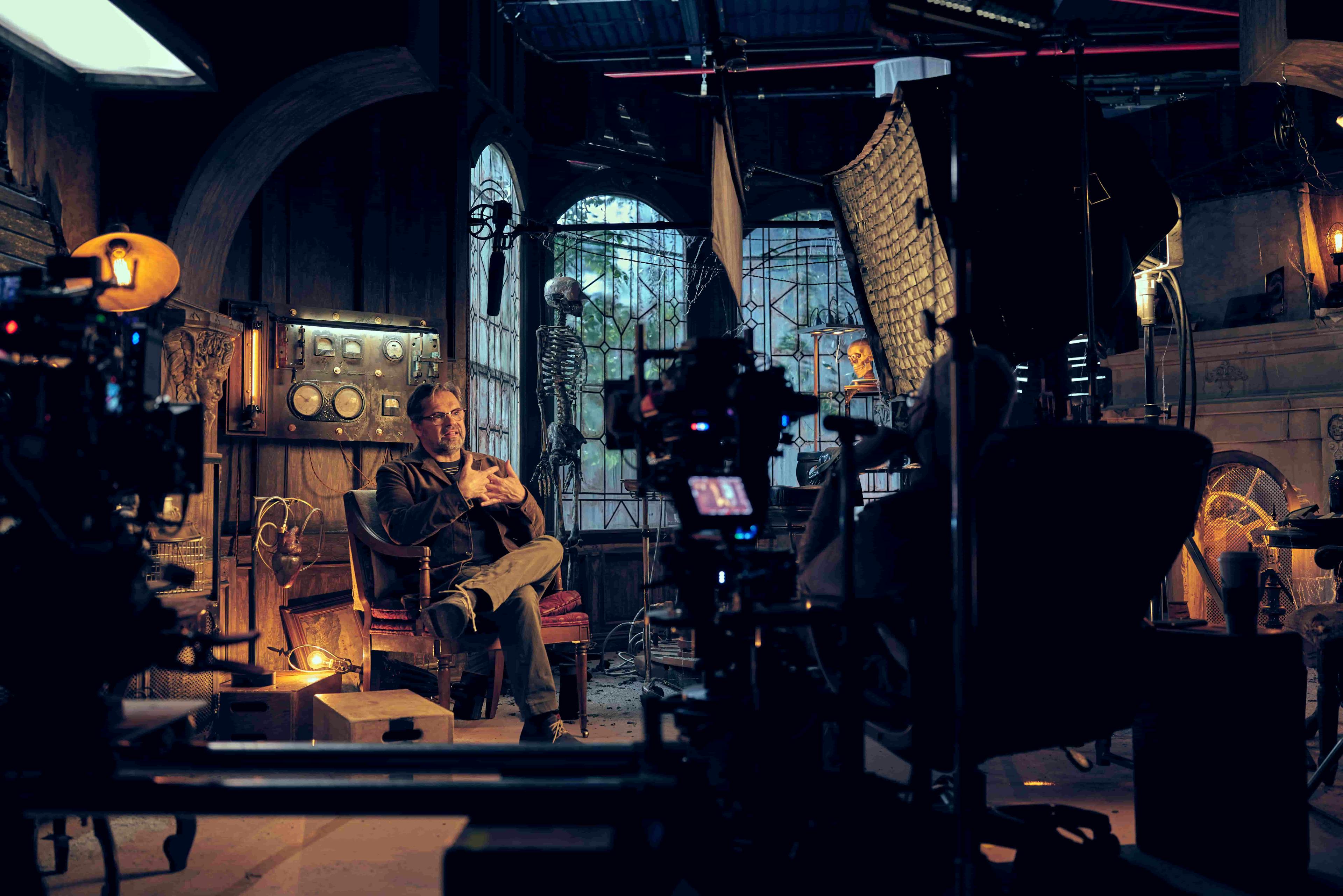 Behind the scenes shot of a man being interviewed with a horror background