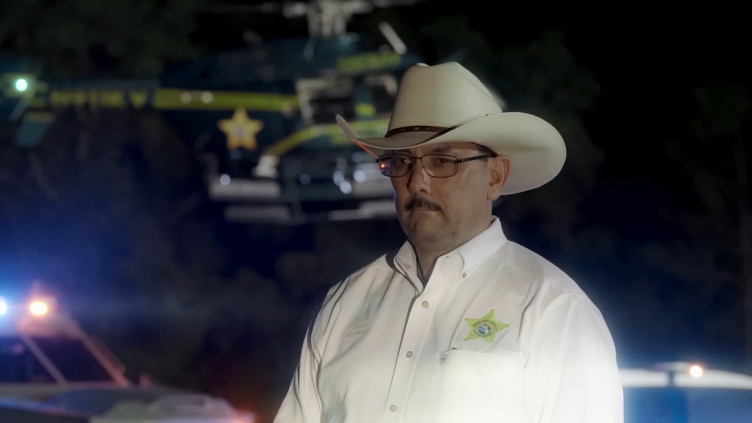 Man in cowboy hat stood in front of helicopter