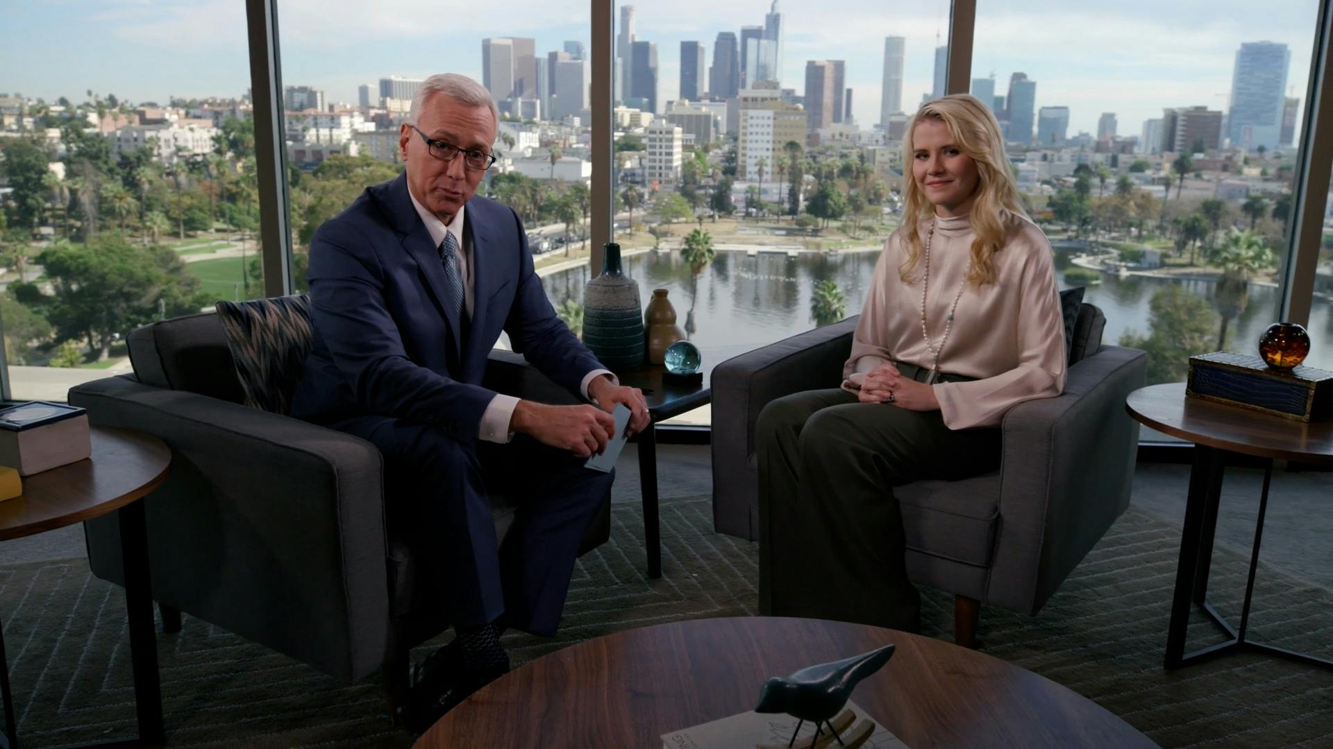 Girl and interviewer sat in chairs looking at camera