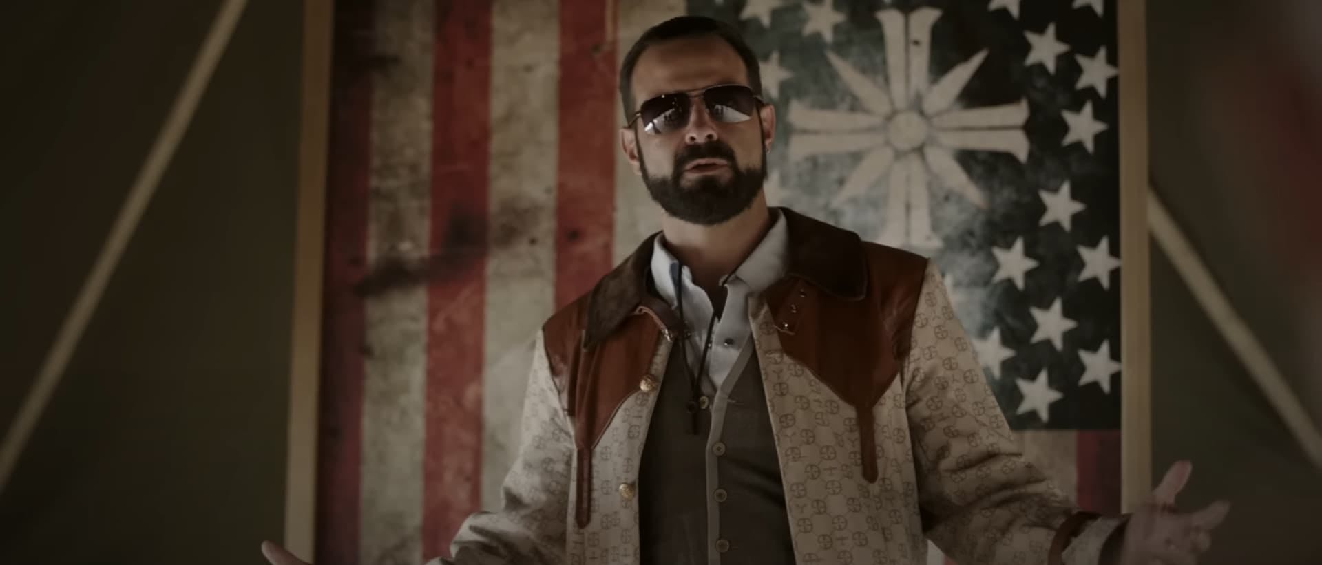 Man wearing sunglasses standing in front of US flag