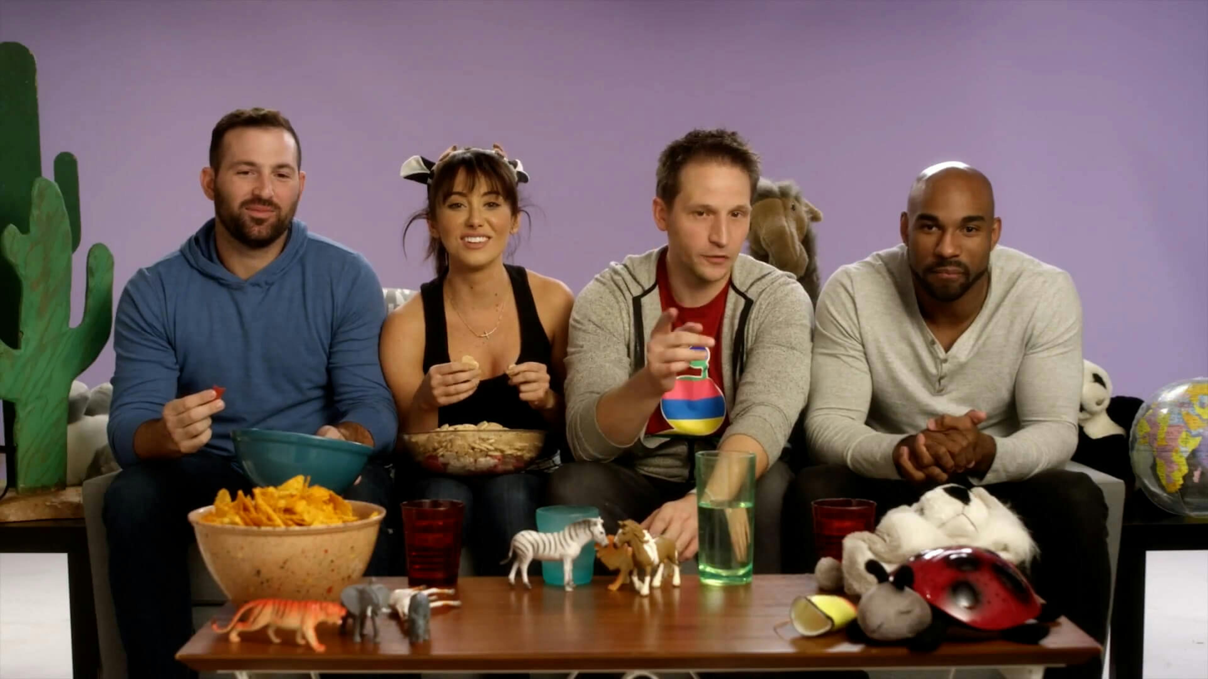 4 people sat on a sofa eating snacks