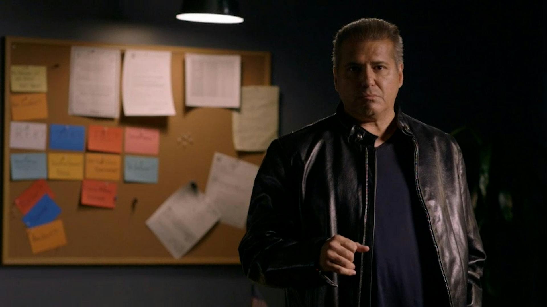 Man in front of cork board with papers on