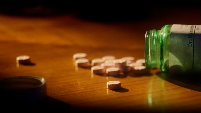Bottle of pills spilt on table