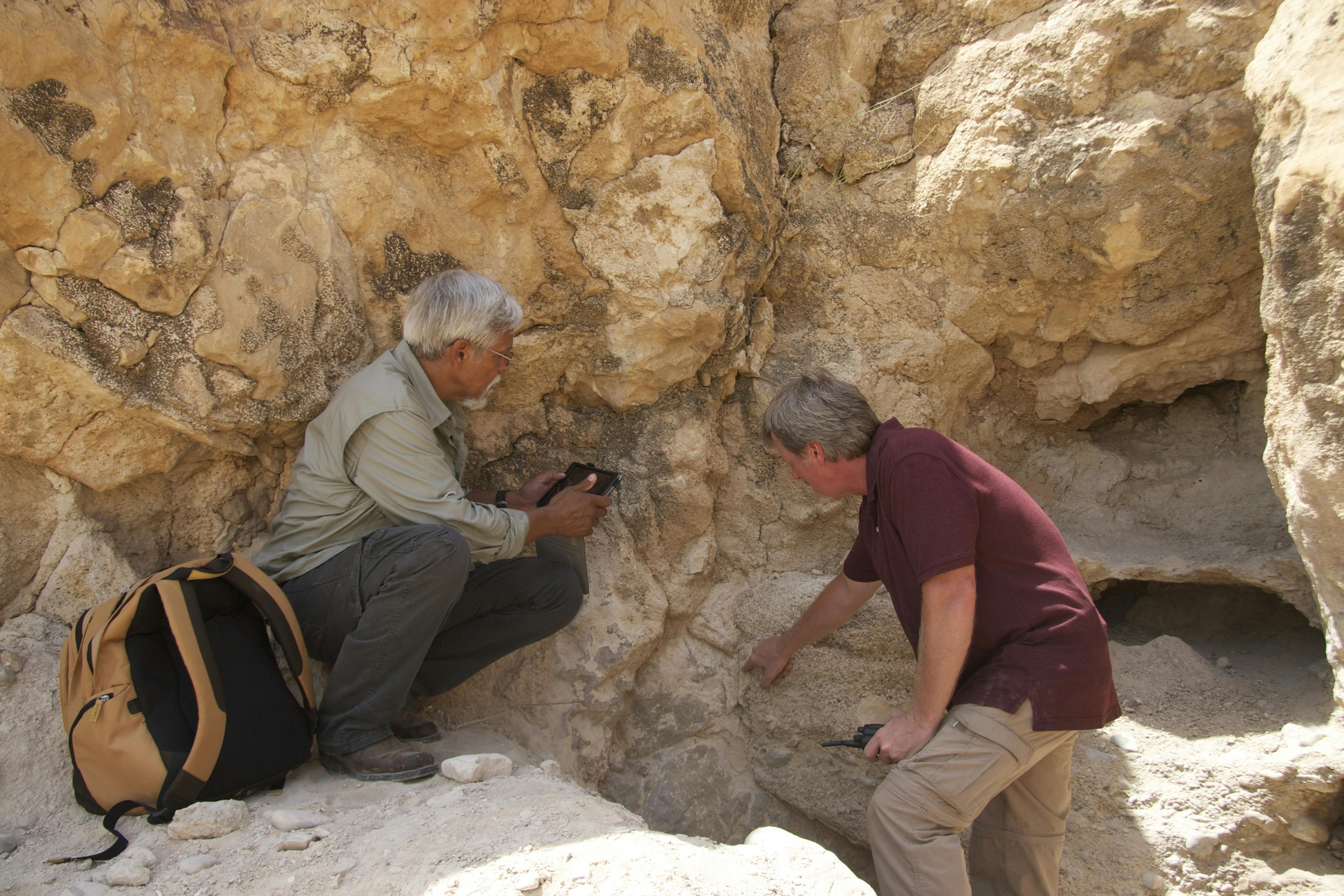 Two men looking at a rock