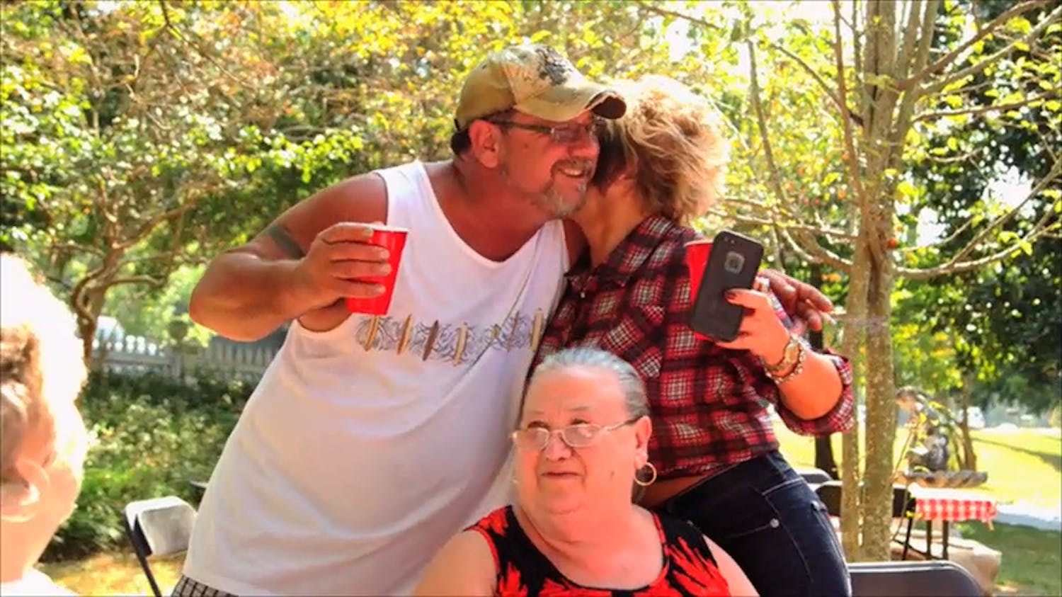 Man and woman hugging whilst holding drinks