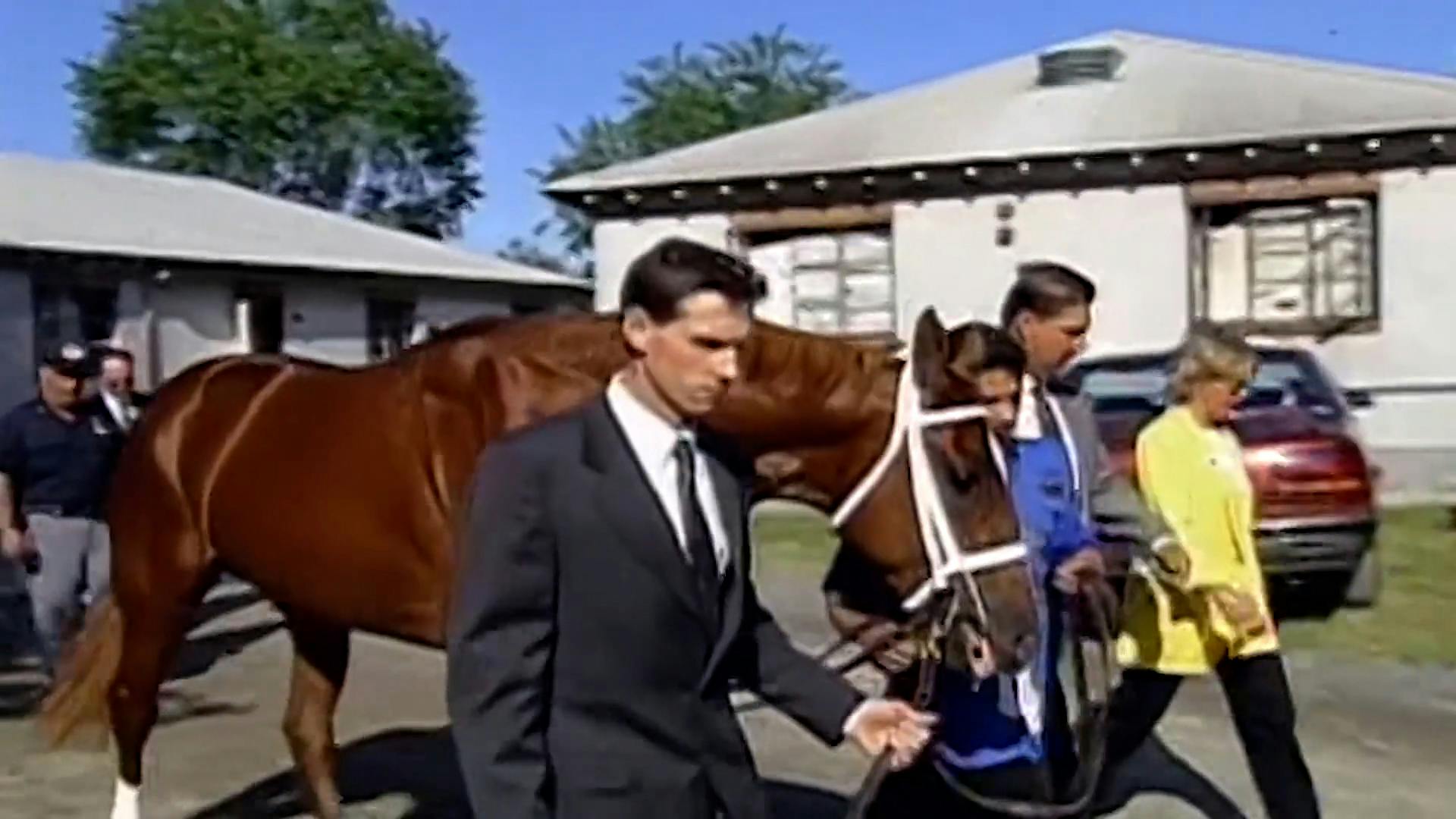 Three people walking alongside horse