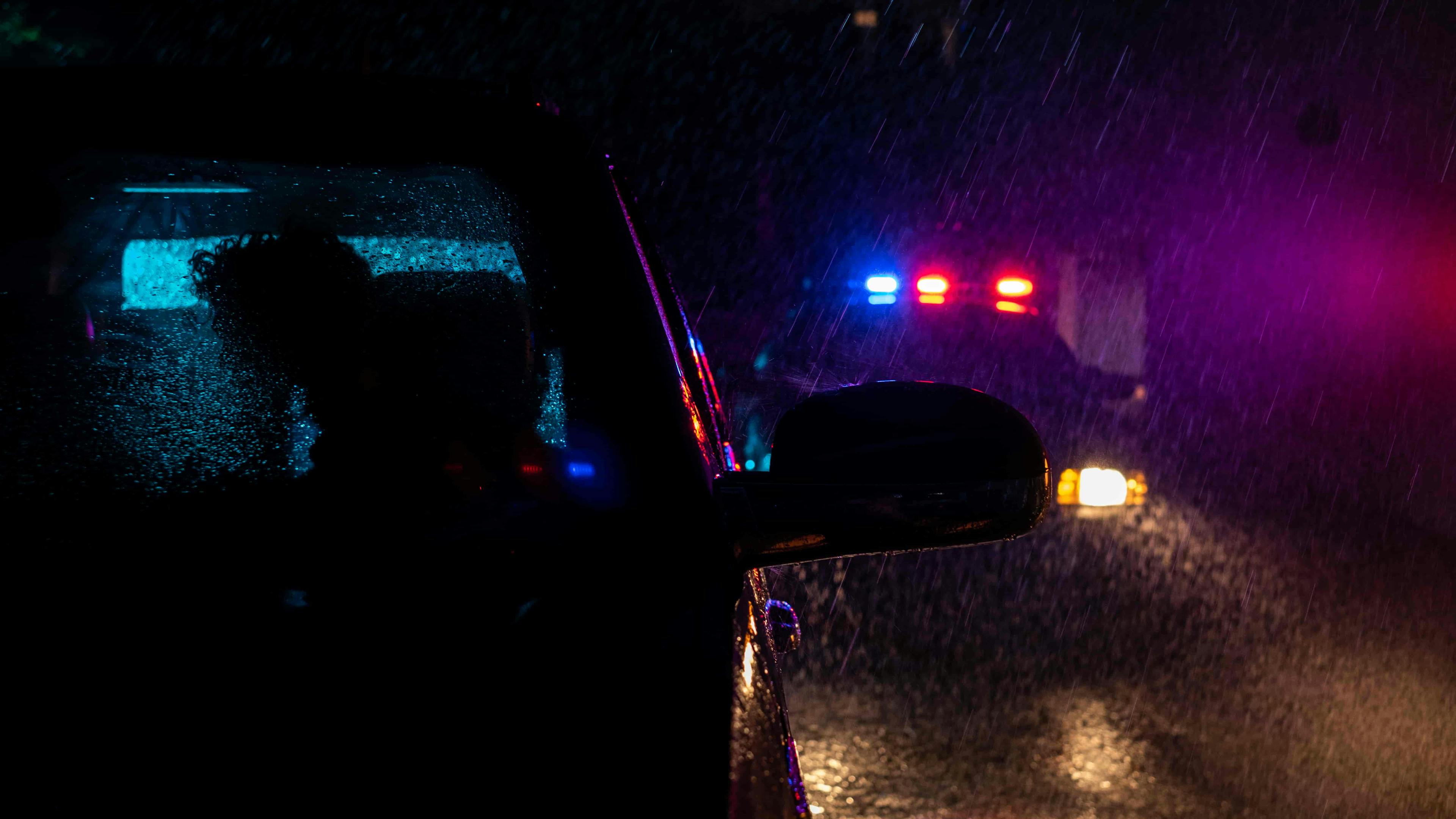 Car with police car behind it in the rain