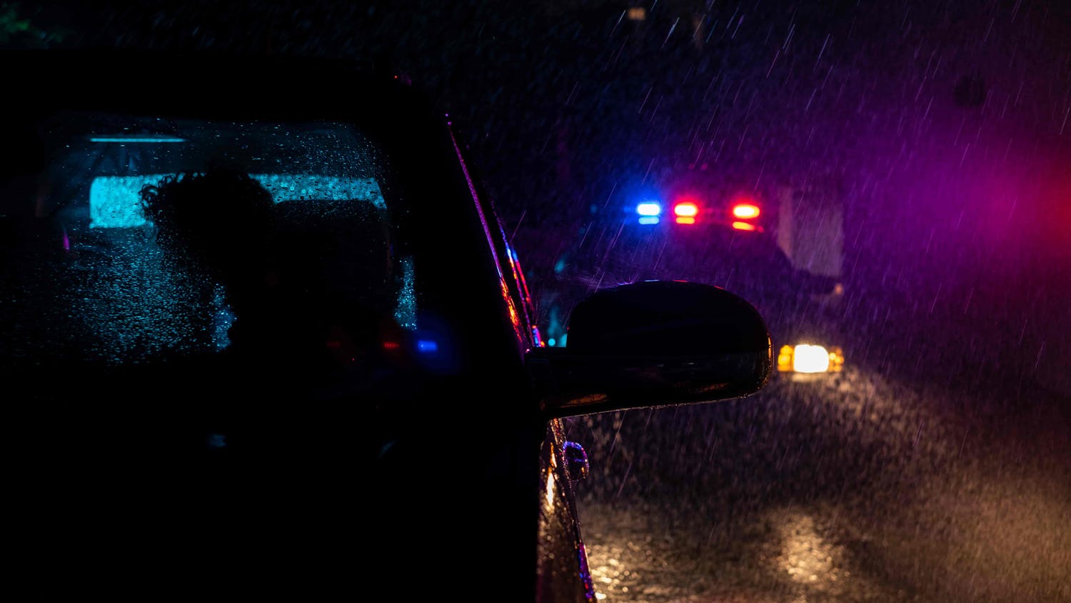 Car with police car behind it in the rain 