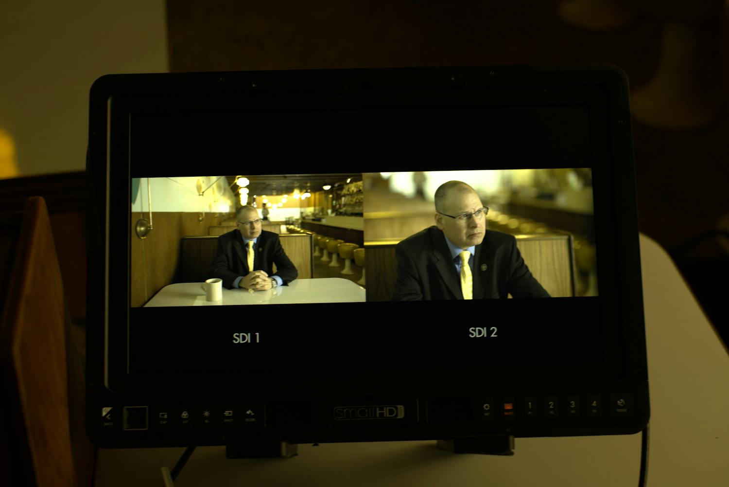 Man being interviewed shown through a screen