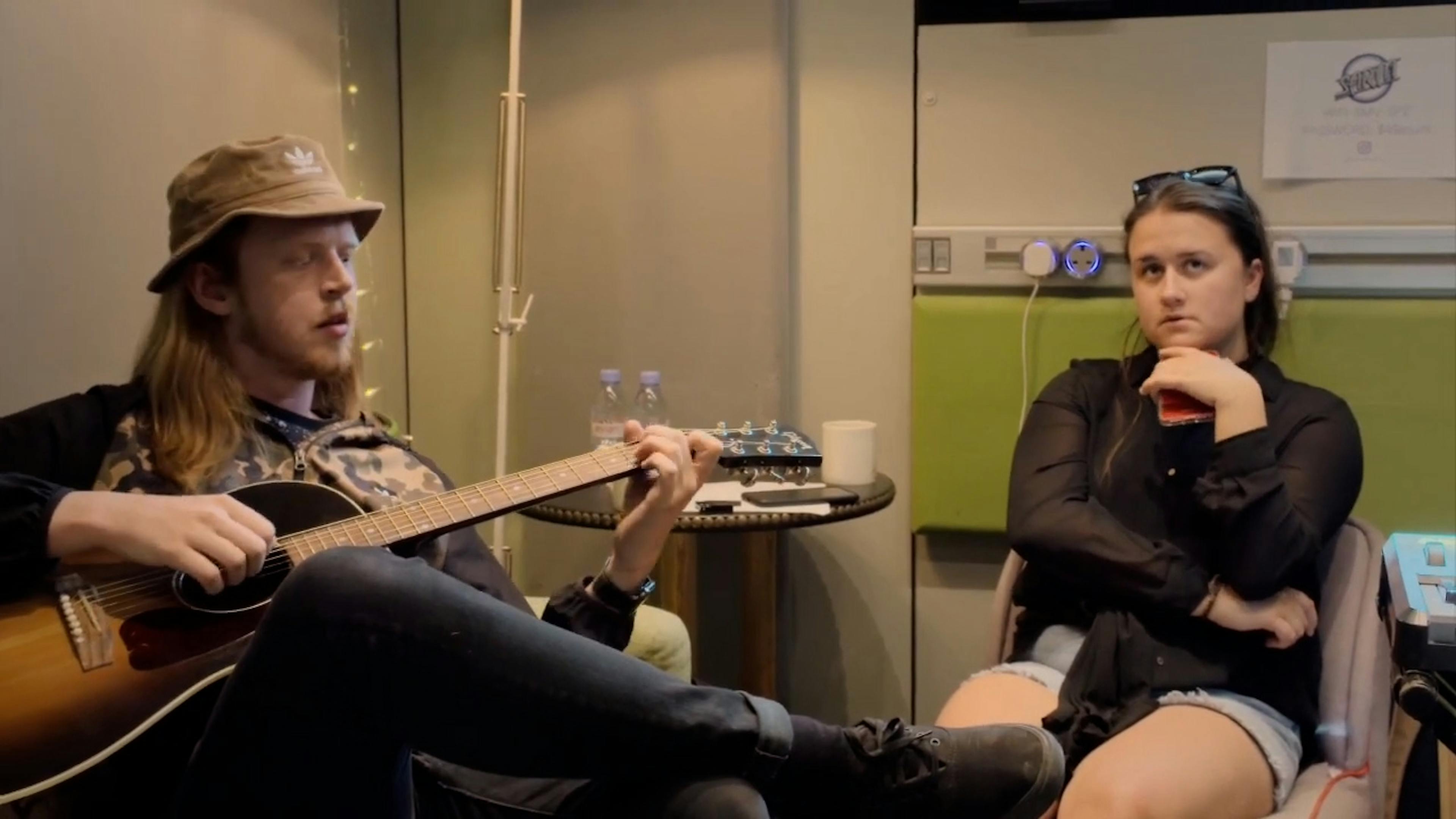 Man playing guitar with girl sat next to him