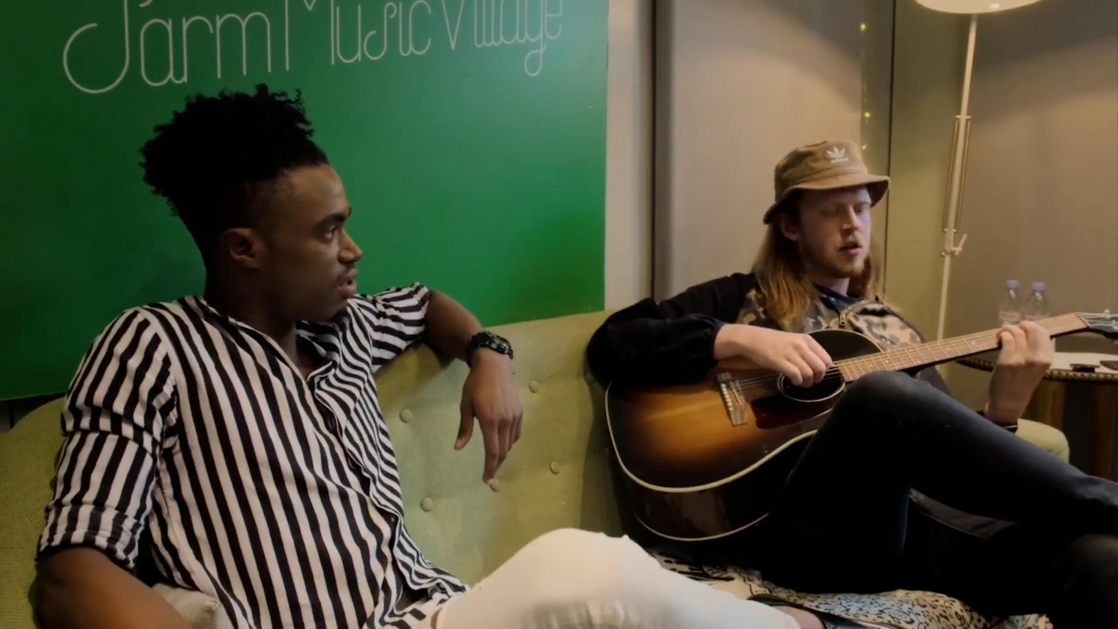 Man playing guitar with man sat next to him