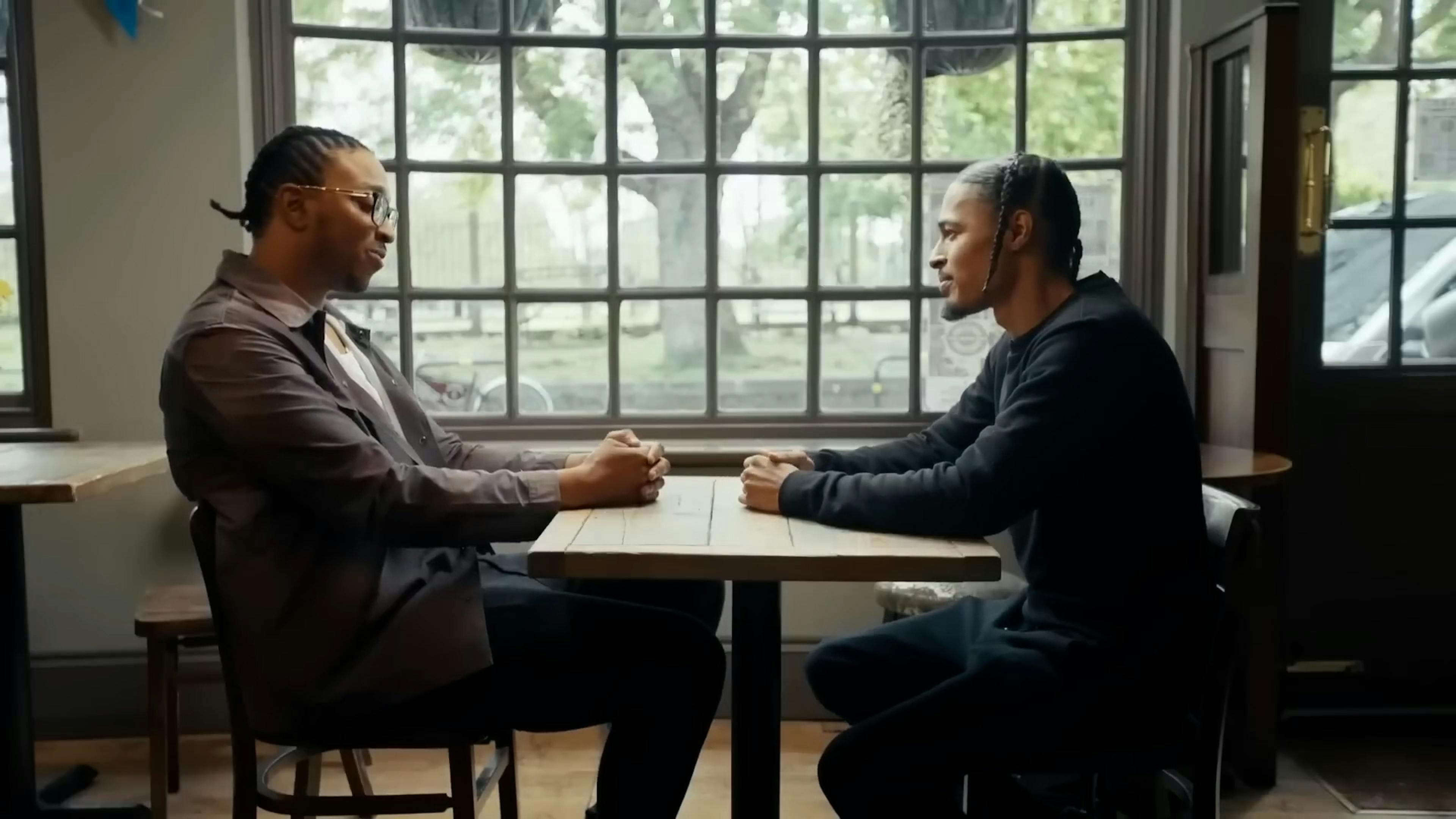Side view of two men talking at table