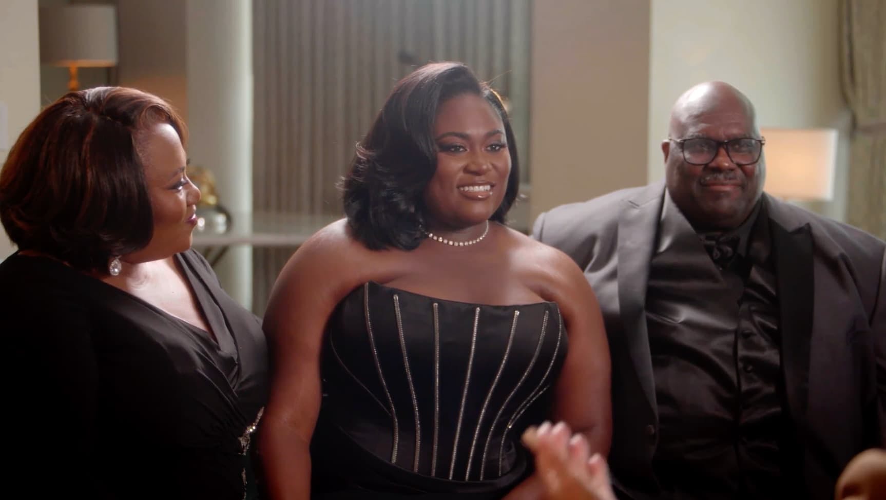 Girl in ball dress with man and woman stood either side of her