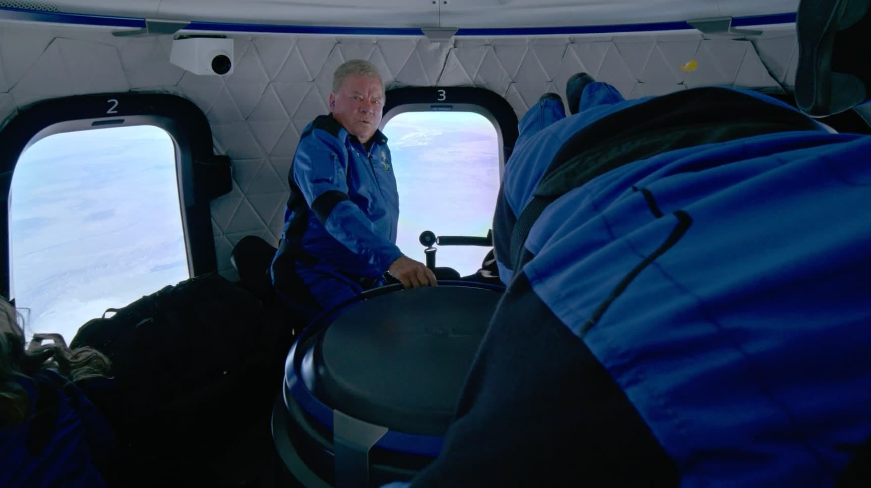 Man in spaceship with another person lay next to him