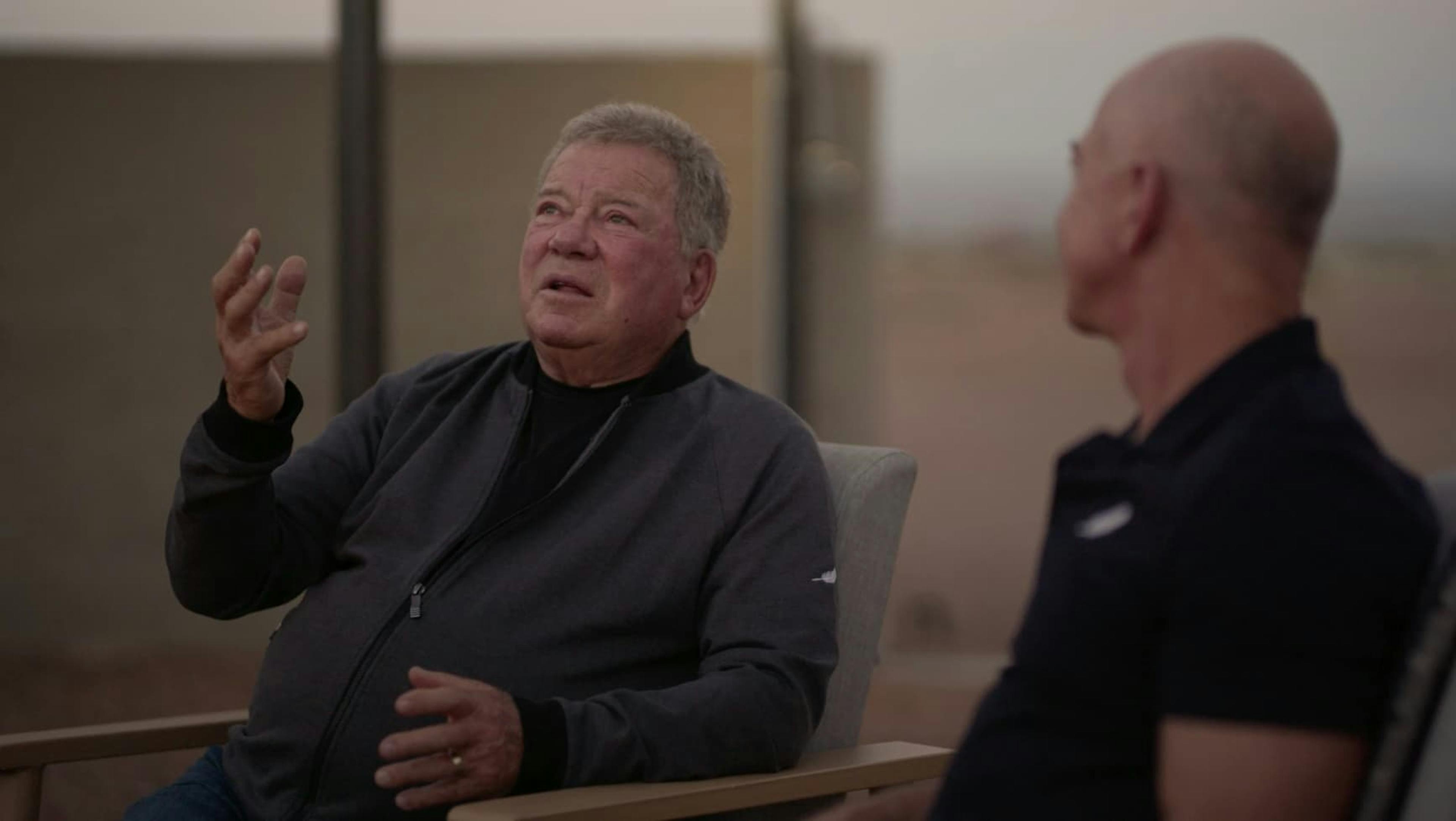 Man talking to another man referencing something in the sky with his hands