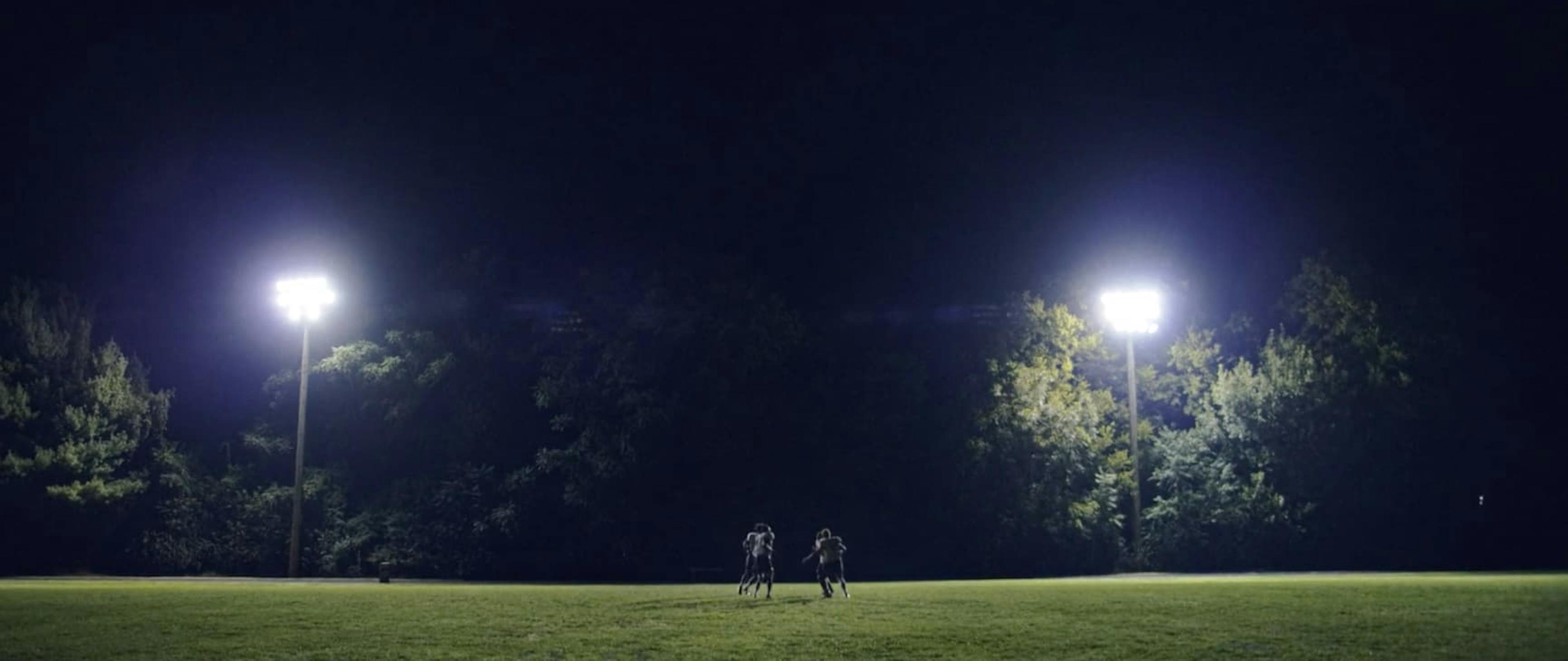 Football pitch in the dark being lit by lights