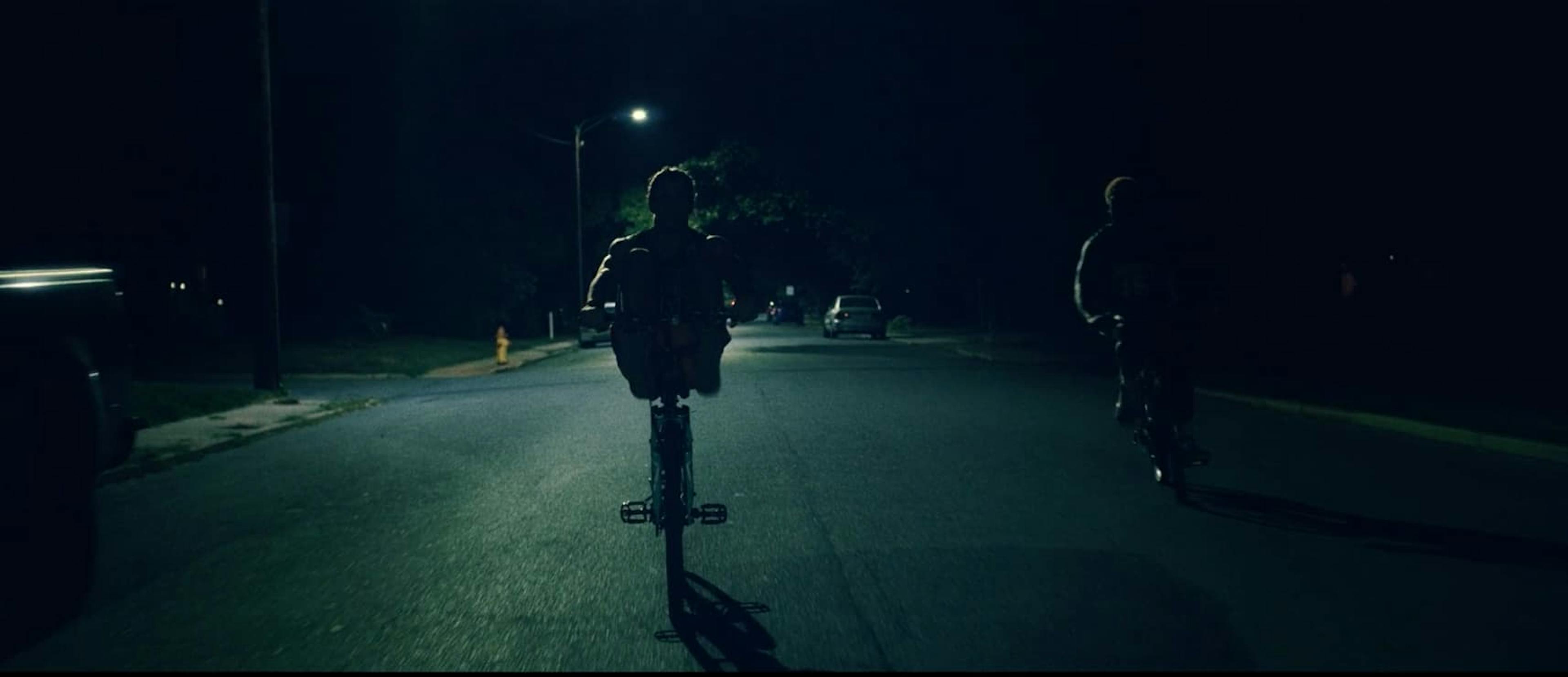 Two people riding bikes in darkness