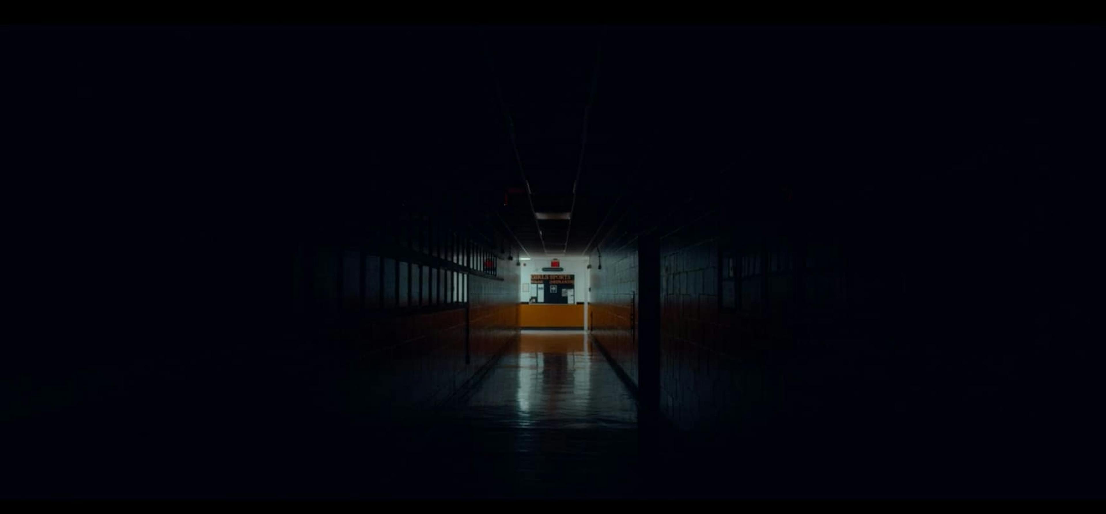 Dark hallway with lit room at the end