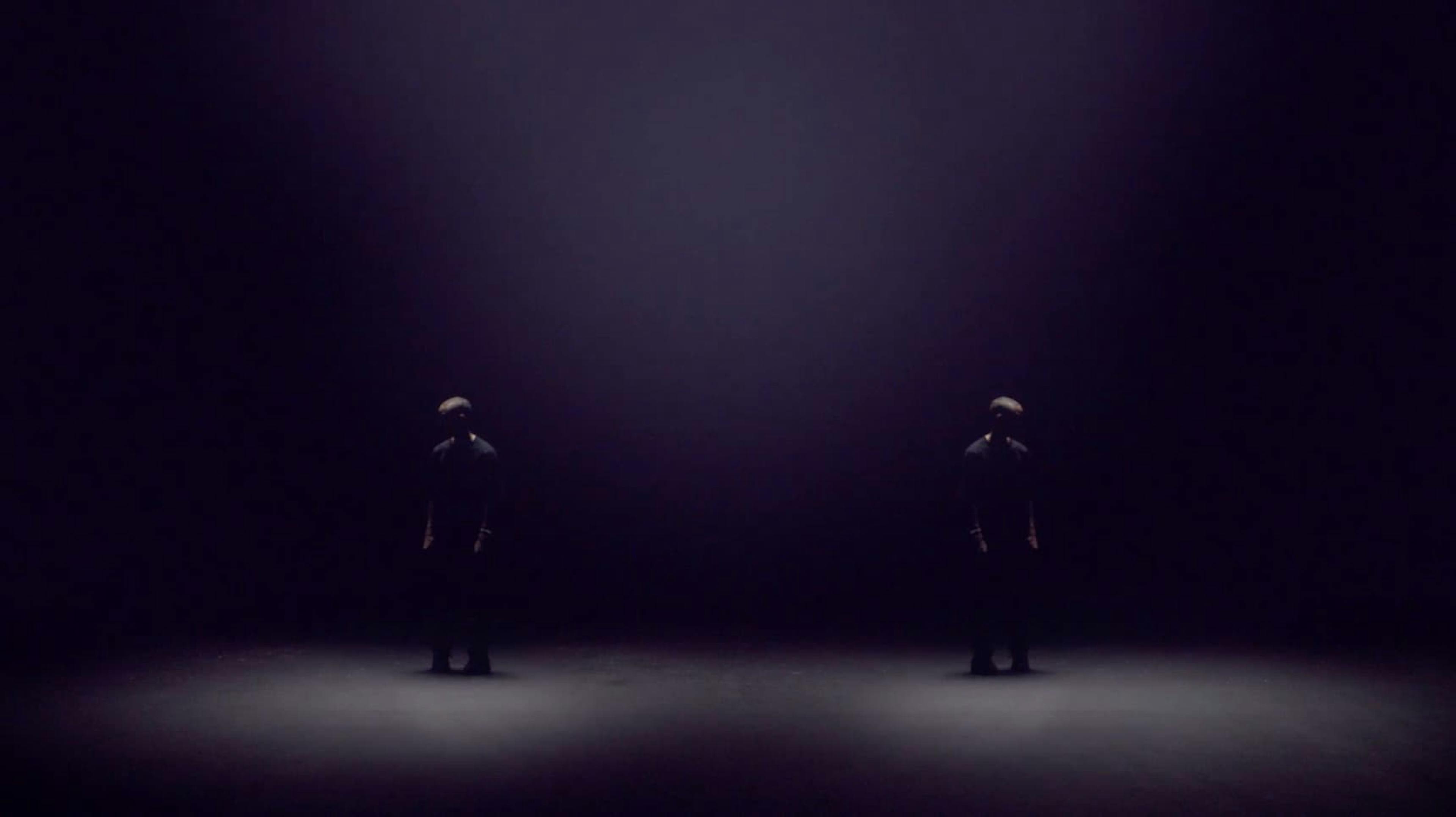 Two men stood apart in a dark room