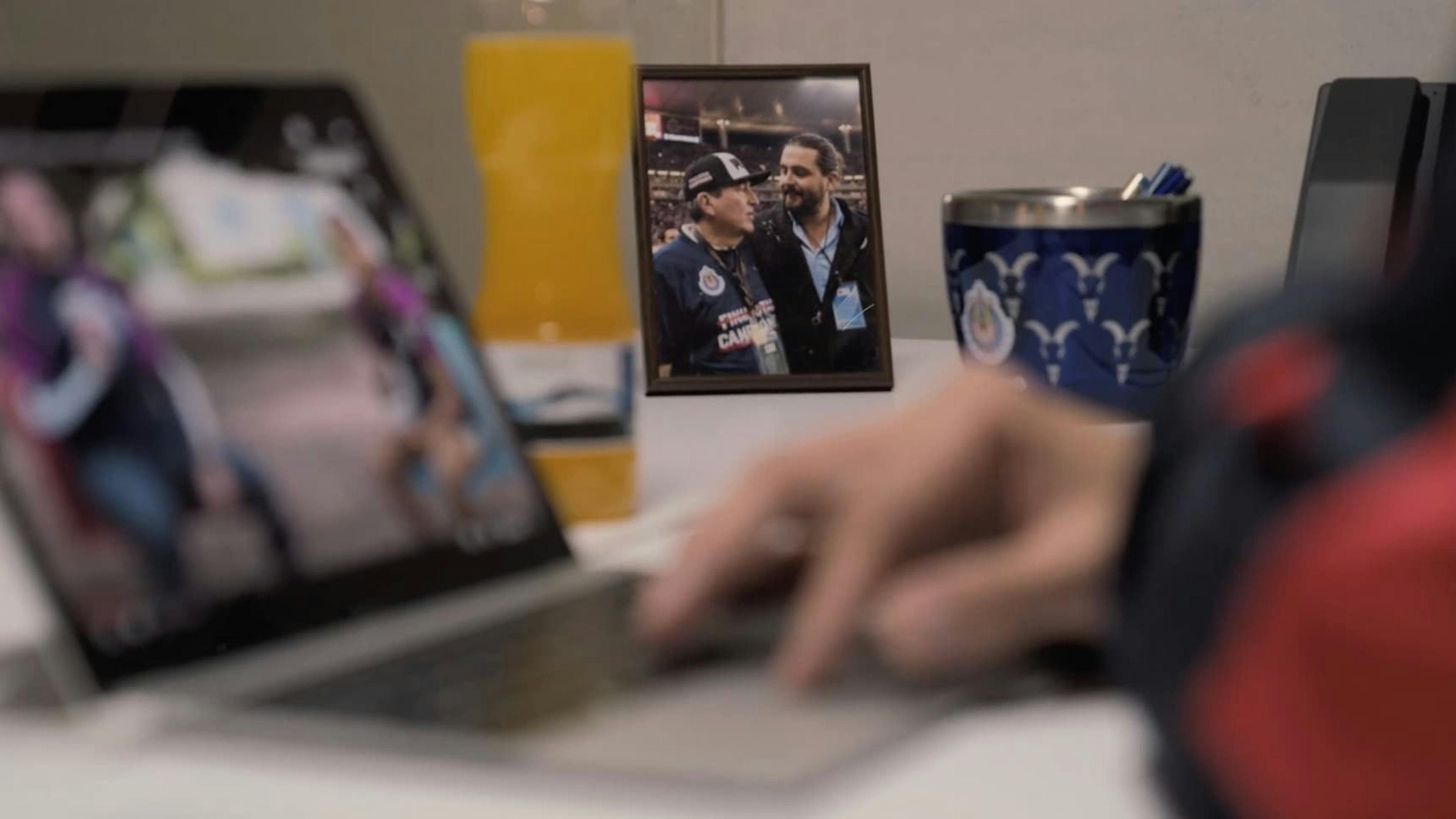 Laptop on table with a photo of two men next to it
