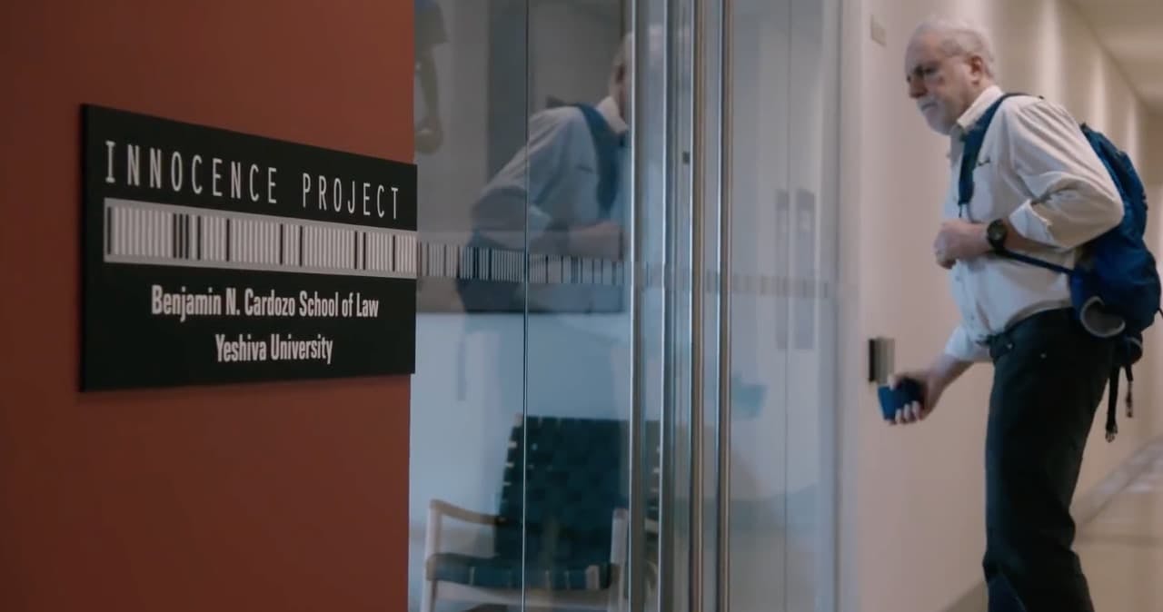 Man walking into an office that has a sign outside saying 'Innocence Project'