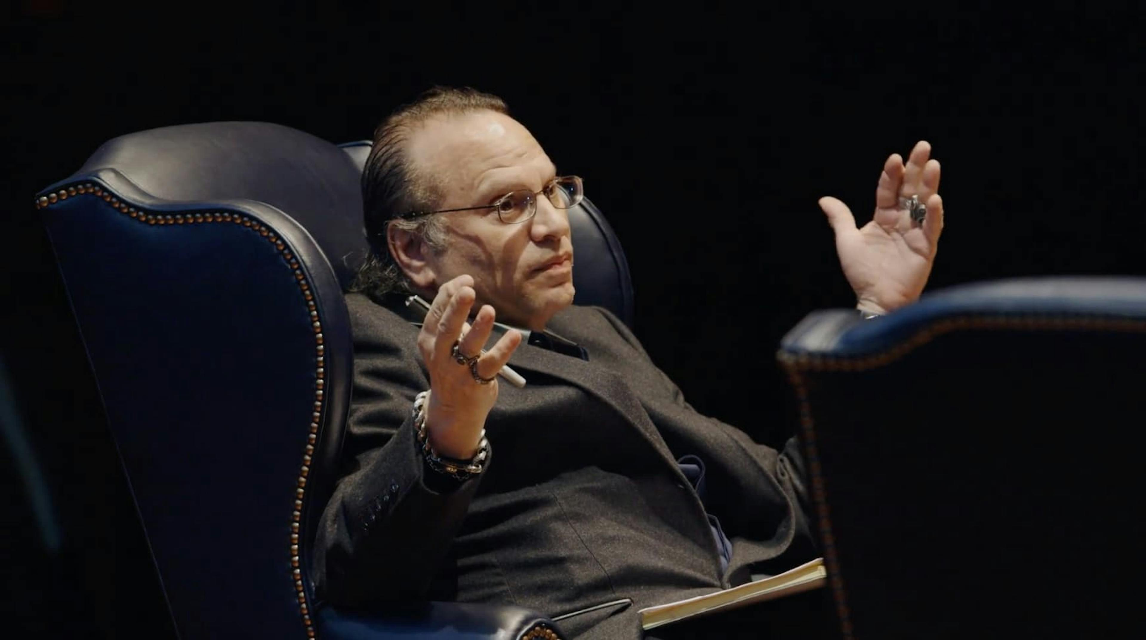 Man sat on chair holding hands up in front of him