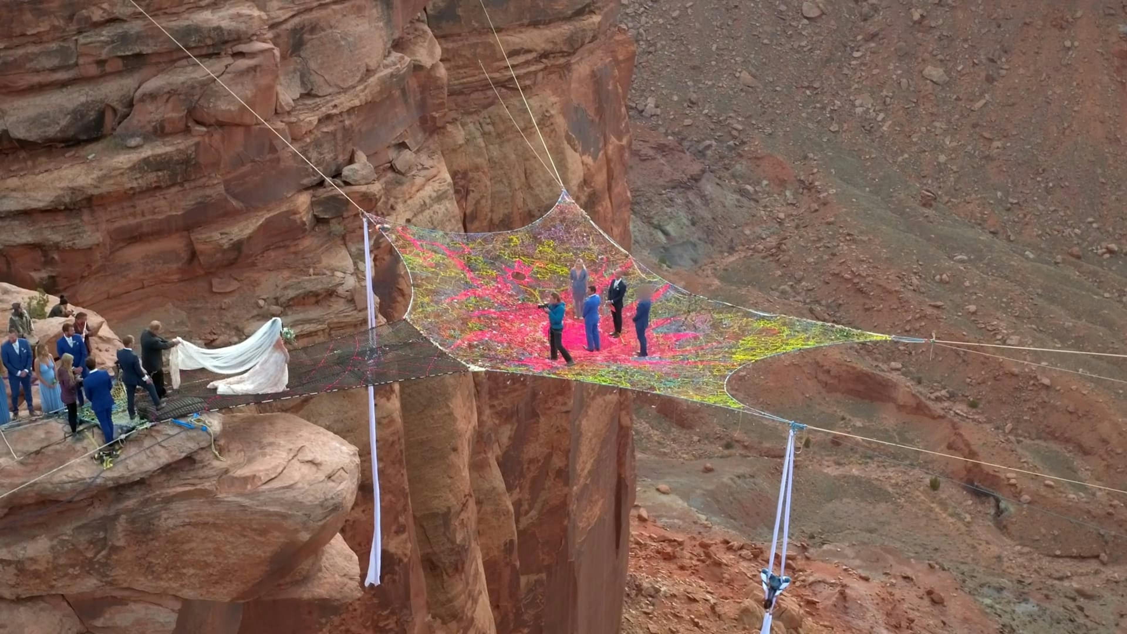 Four people walking on net over canyon