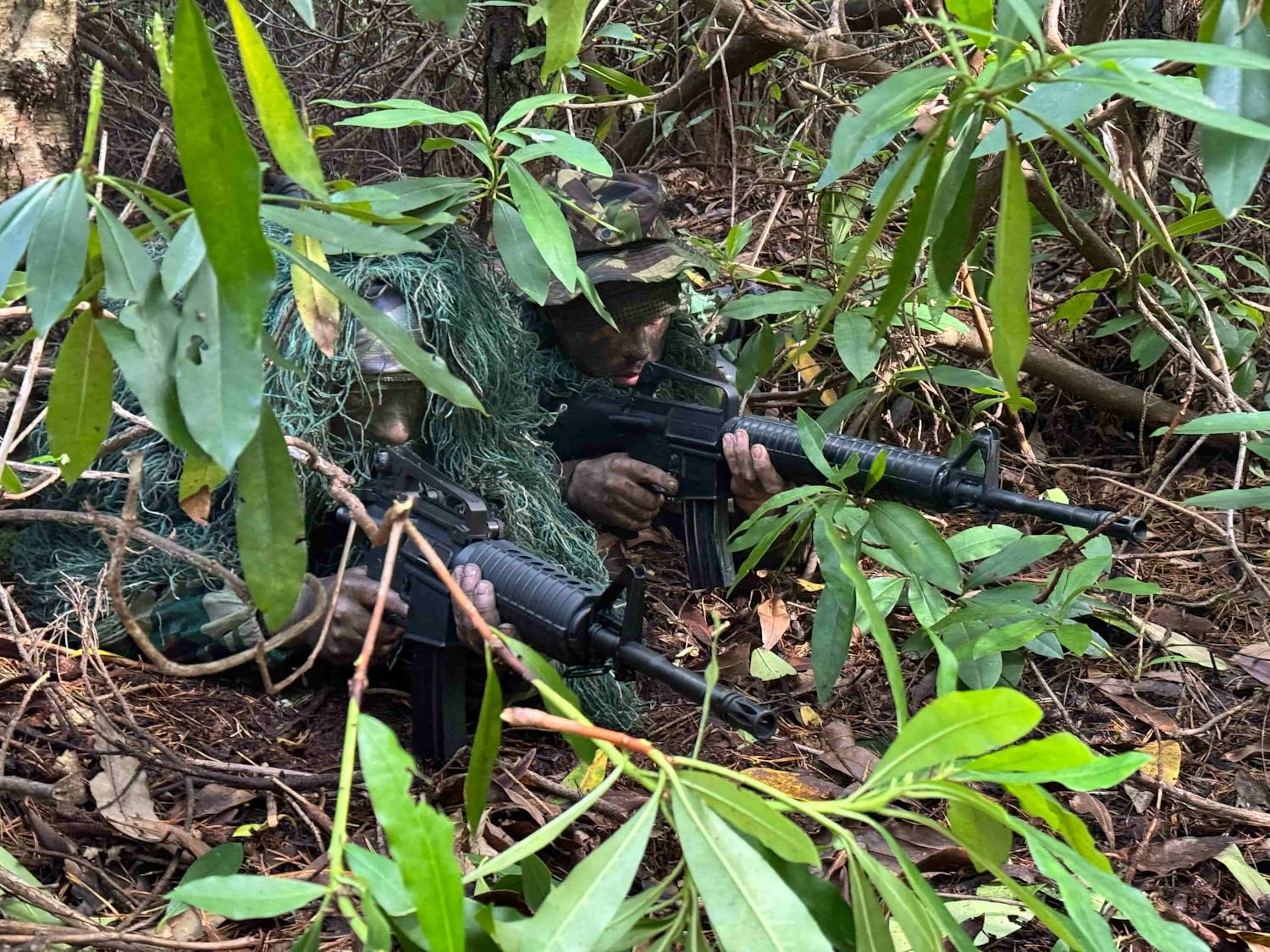 Men with guns crouched down camouflaging