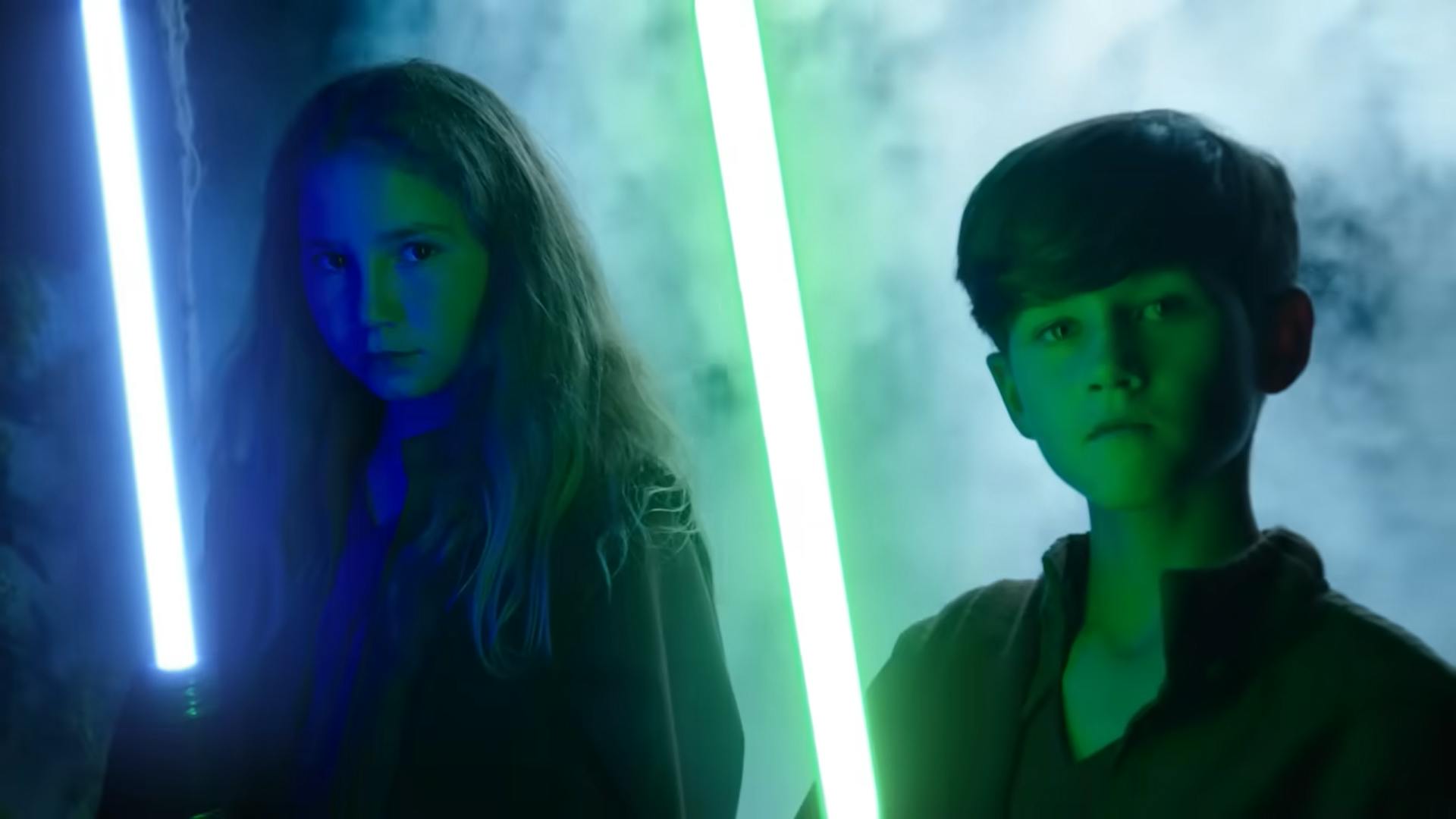 Girl and boy holding lightsabers